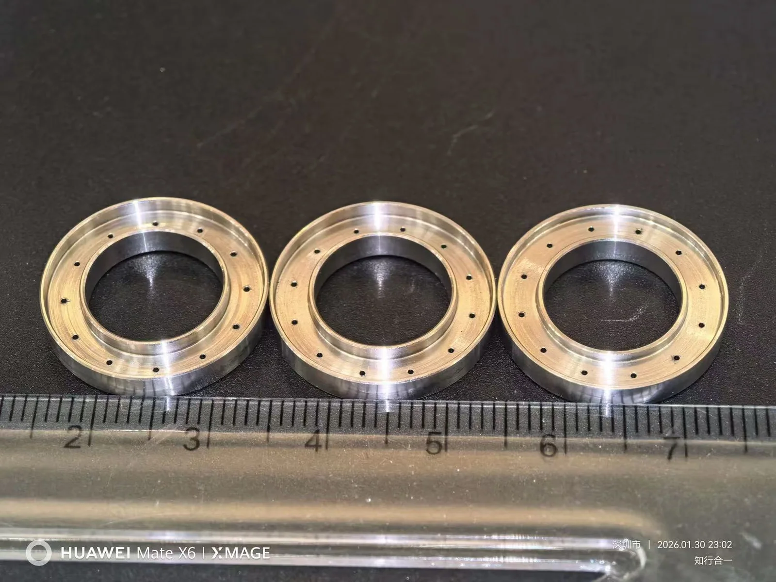 Three machined circular bodies with prepared holes before welding and assembly